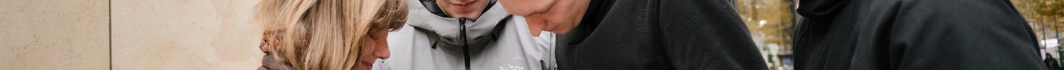 Vier junge Leute schauen auf ein Smartphone und suchen einen FreD Standort.