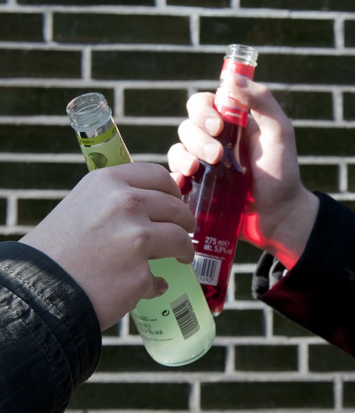 Zwei Jugendlichen stoßen mit Alkopop-Flaschen an.