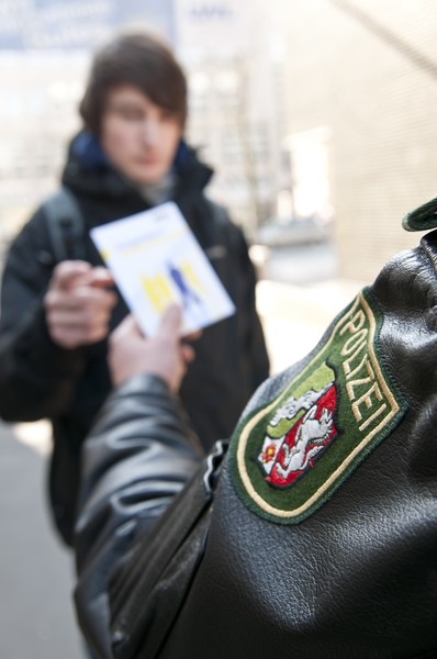 Ein Polizist übergibt einem Jugendlichen den Flyer "Aufgefallen?"